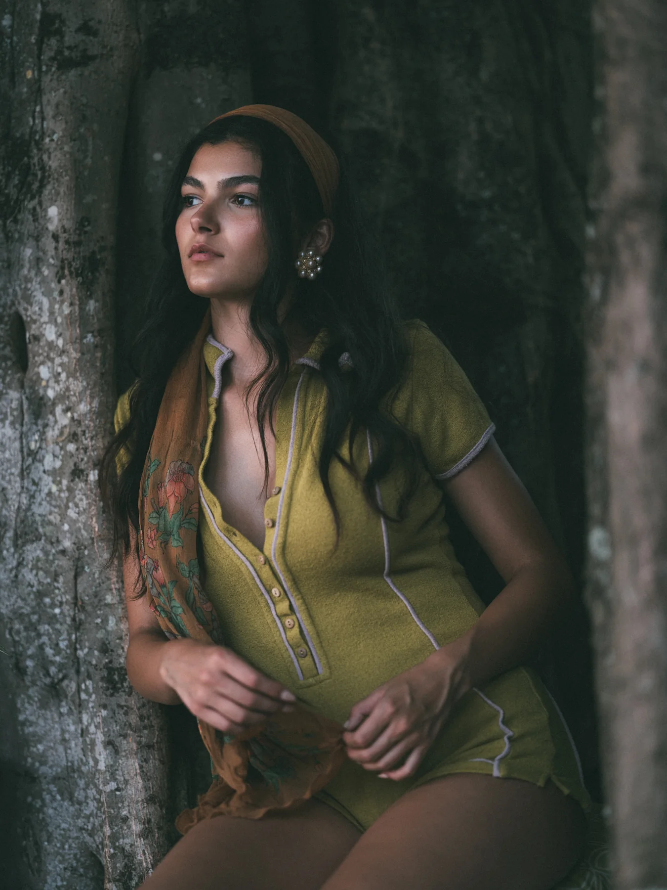 Alexis Santiago in a green knit outfit standing beside a tree trunk