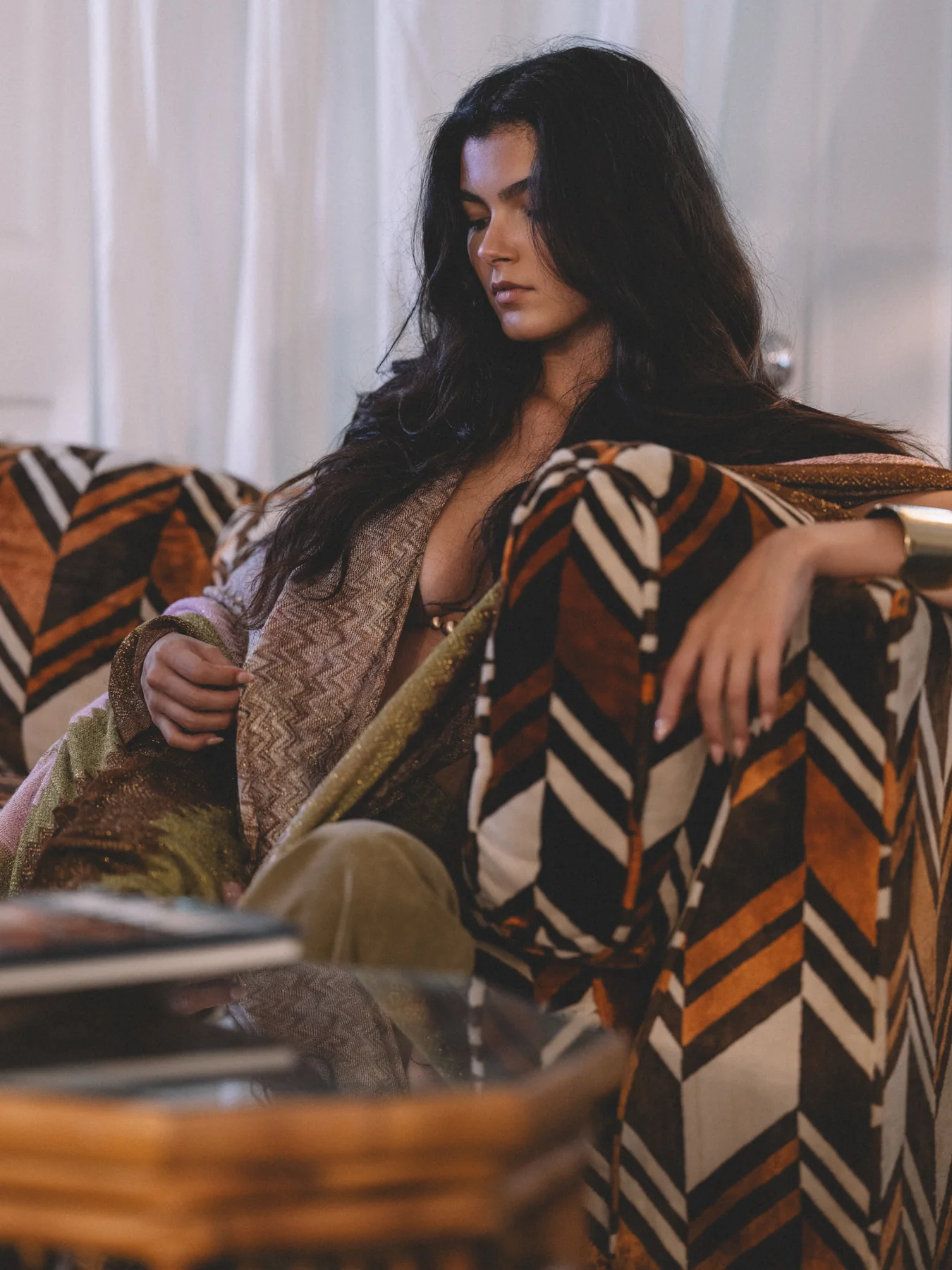 Alexis Santiago reclining in a patterned armchair beside a window