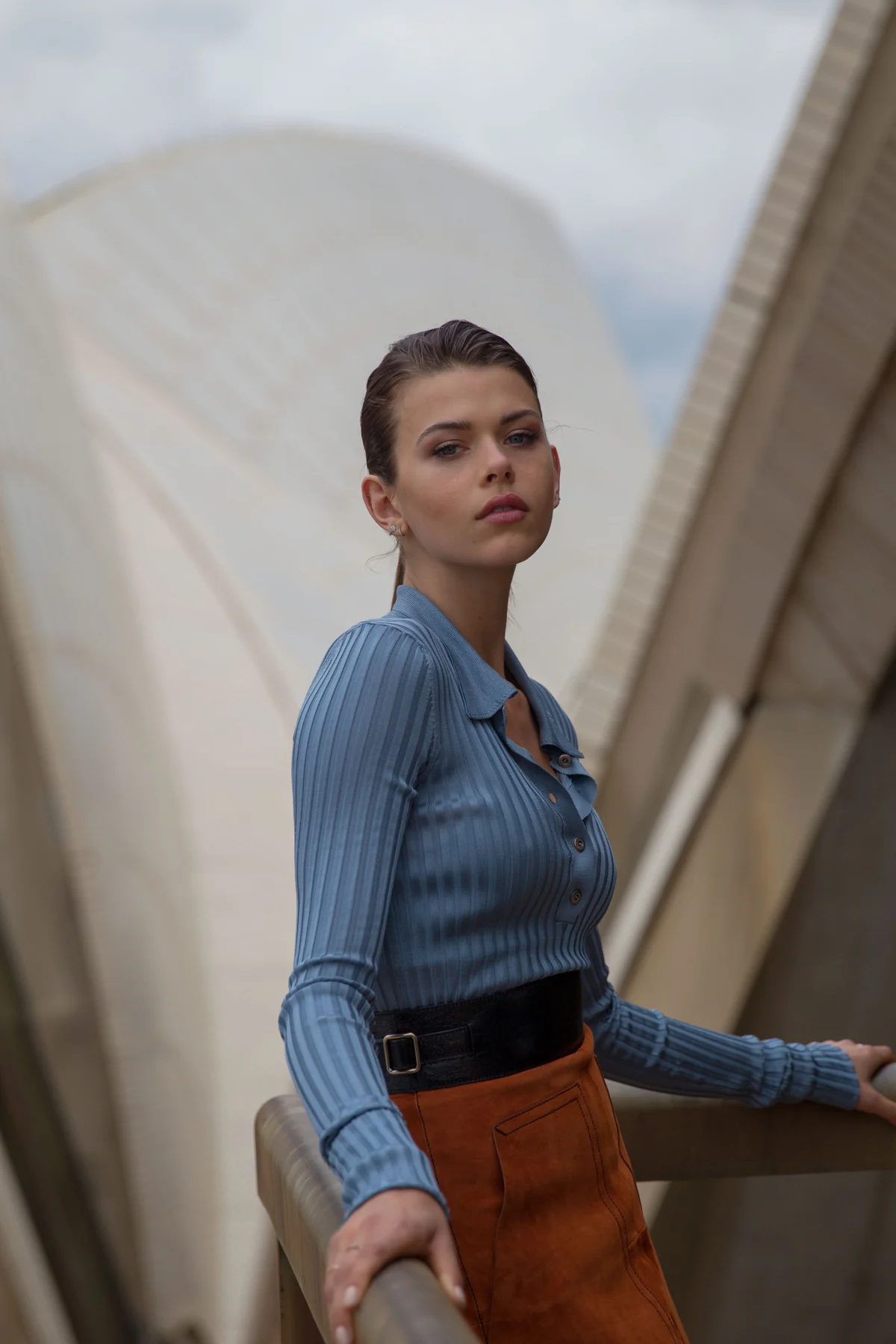Fashion portrait of a model in a blue collared top beside the Sydney Opera House
