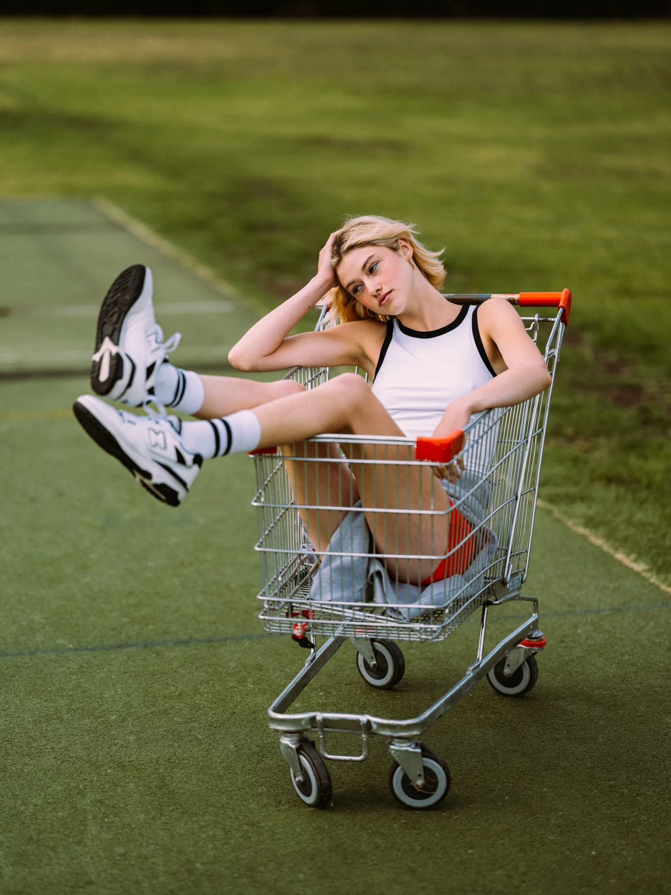 Gracie Rae reclining in a shopping trolley on an outdoor sports court