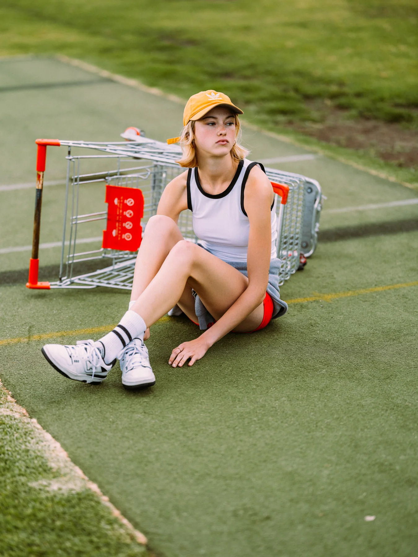 Gracie Rae in a mustard cap seated beside an overturned shopping trolley