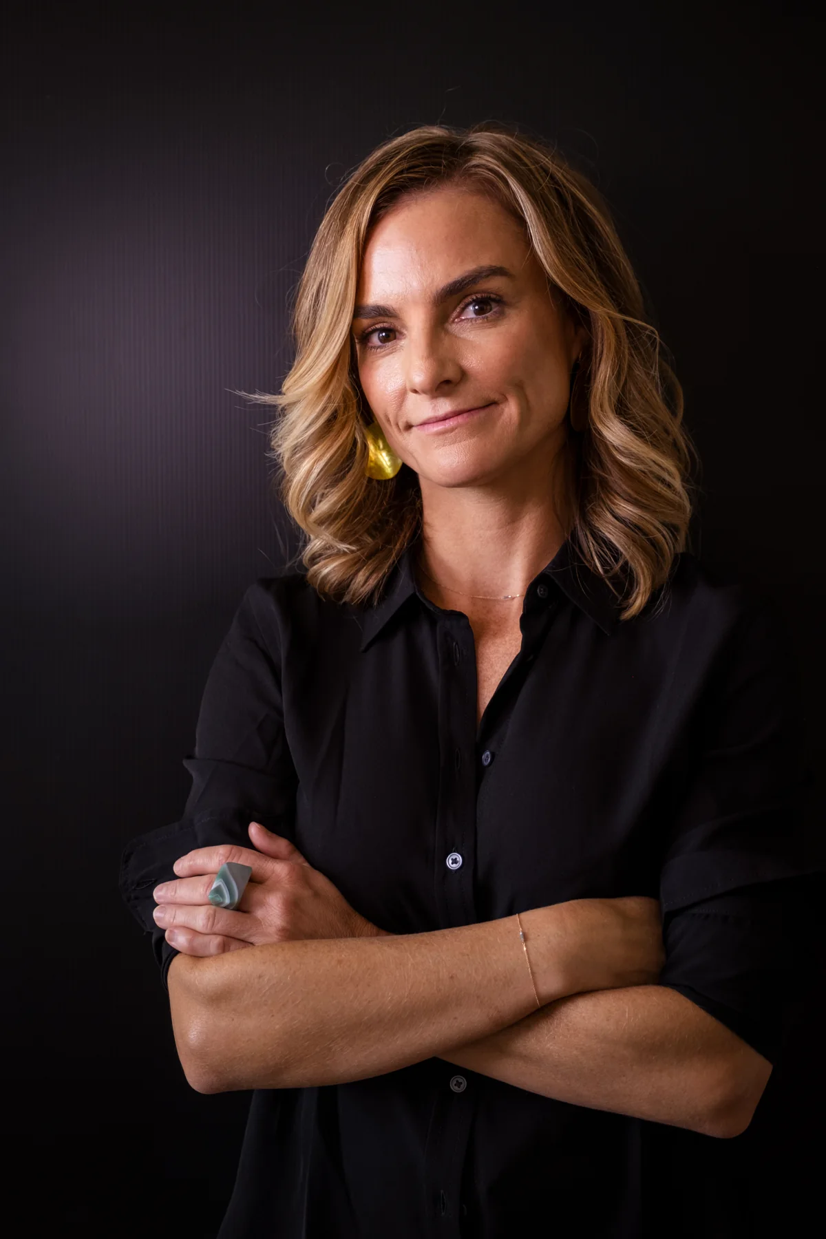 Lindy in a black shirt, photographed at an angle with folded arms
