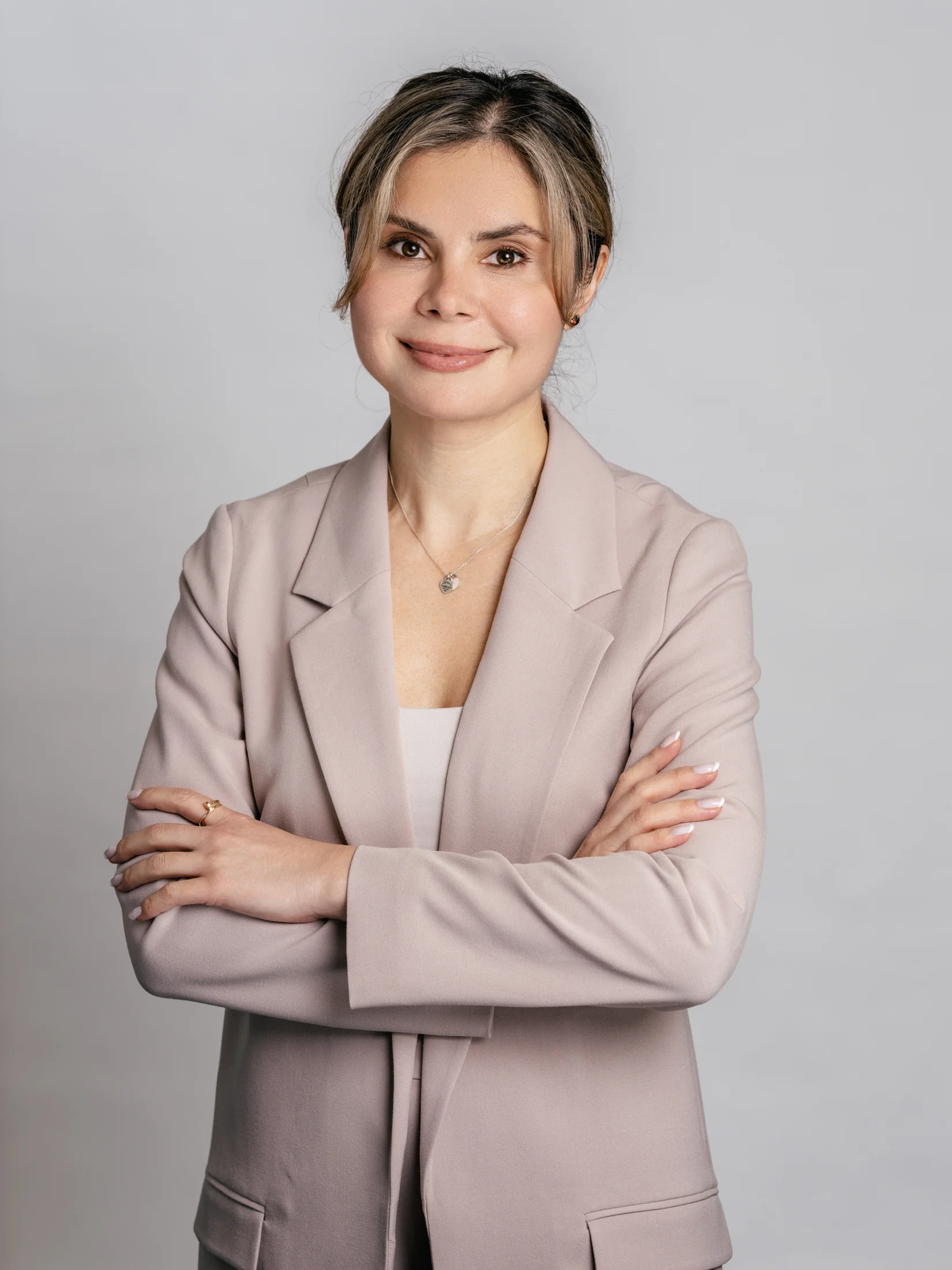 MDC staff portrait in a pale blazer with folded arms against a grey background