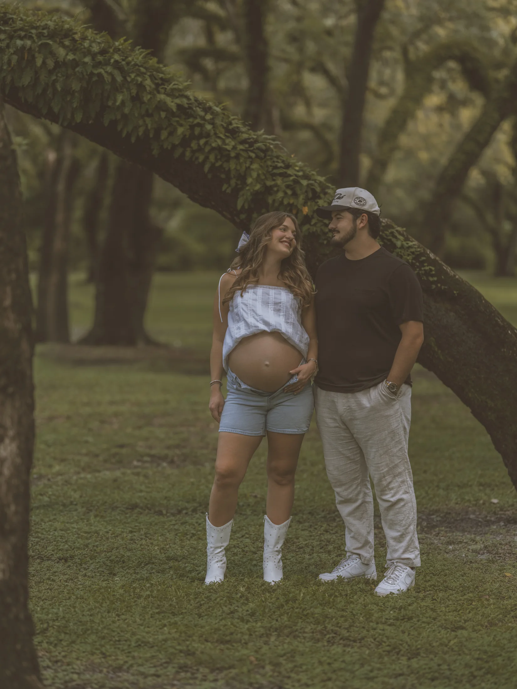 Kelsey and her partner standing together beneath spreading tree branches
