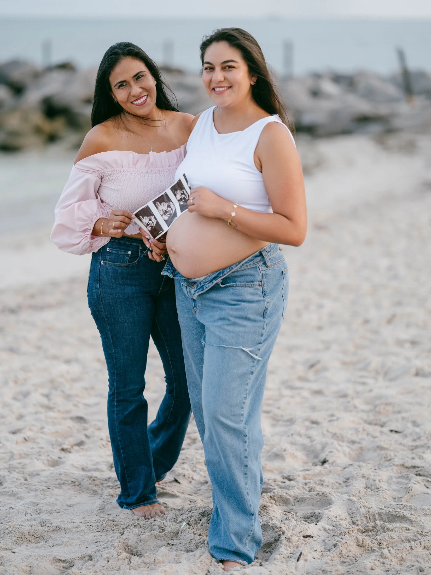 Michelle and a companion holding ultrasound photographs on the beach